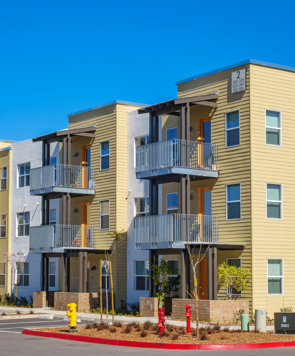 Modern yellow and white apartment building exterior on a sunny day.