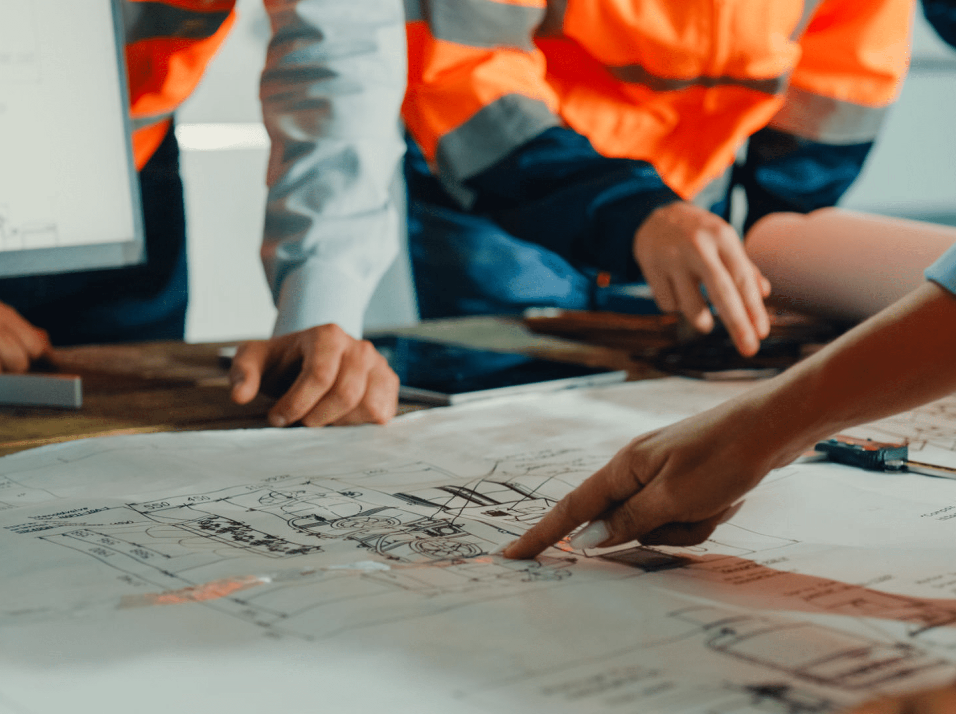 Engineers reviewing and pointing at technical plans on a table.